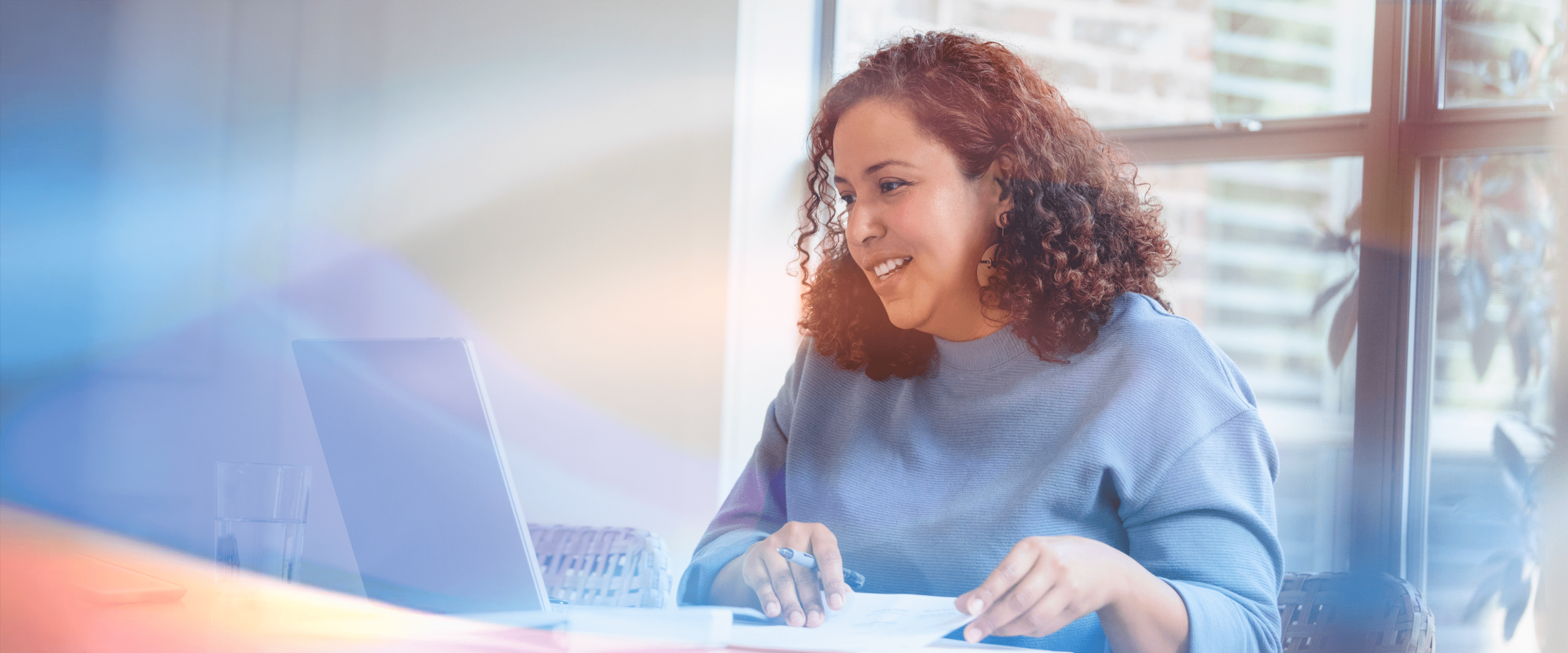 Lächelnde Frau mit Locken vor dem Laptop